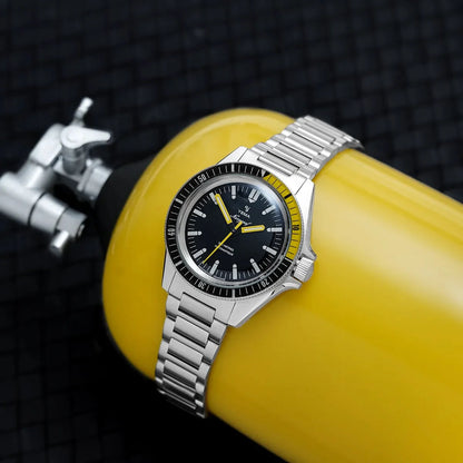 Yema Navygraf CMM.10 noire et jaune — montre portée sur une combinaison de plongée jaune