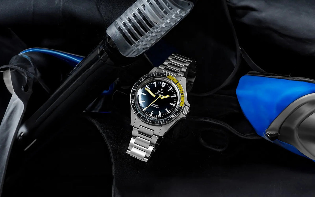 Yema Navygraf CMM.10 noire et jaune — montre sur bracelet acier près d’un masque de plongée