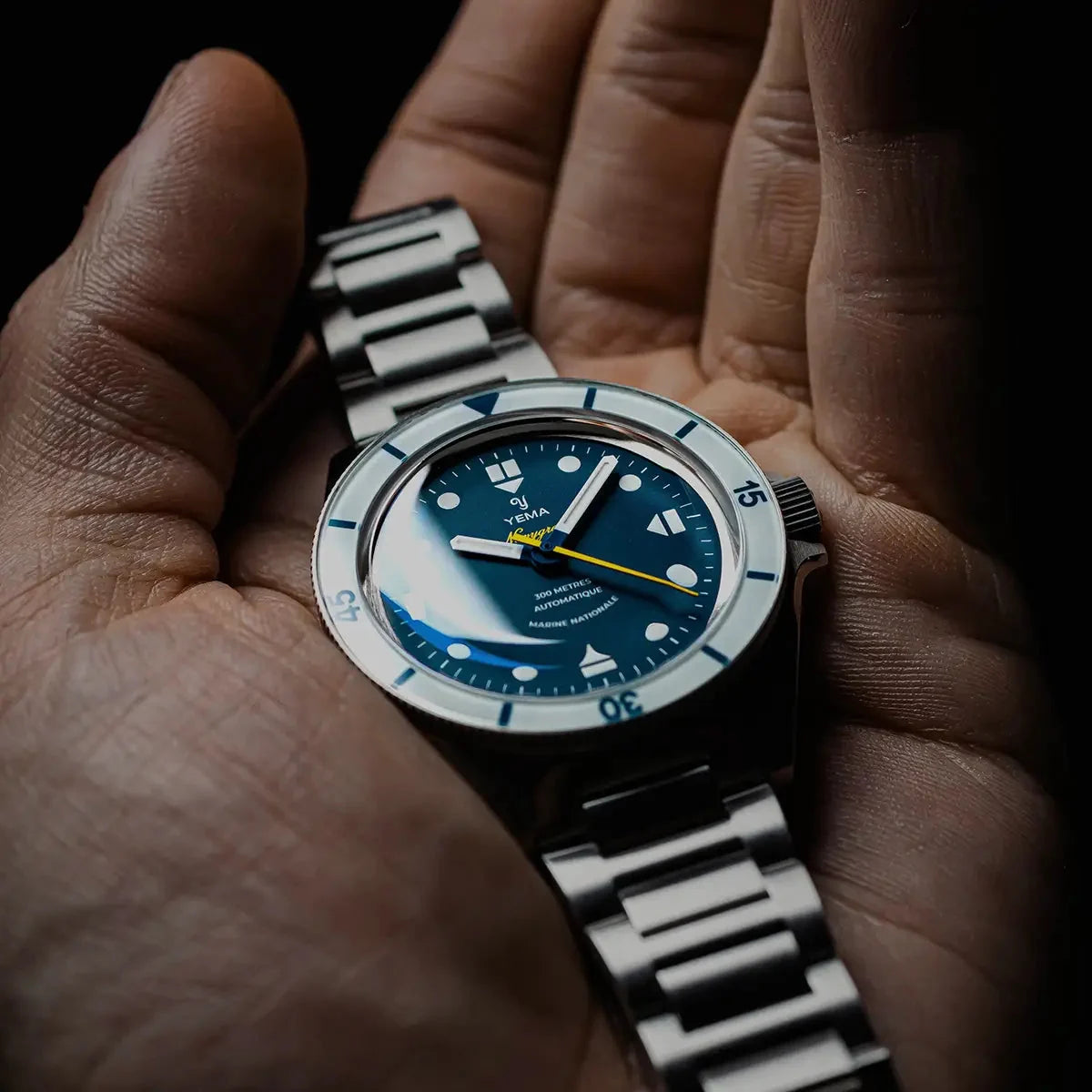 Yema Navygraf Marine nationale CMM.10, lunette blanche — montre tenue en main sur bracelet acier